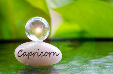 Capricorn text engraved on Zen stone with shining glass marble on top. Zodiac concept
