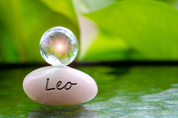 Leo text engraved on Zen stone with shining glass marble on top. Zodiac concept