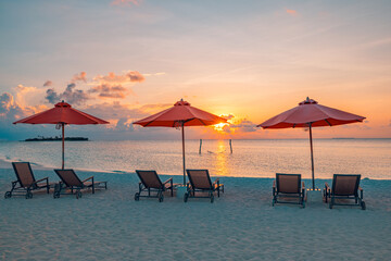 Romantic sunset view. Sandy shore soft sunrise sunlight over lounge chairs umbrellas. Tropical...