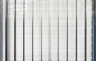 Texture of vertical fluted glass, or striped glass, with the refraction of lights behind it. Fluted glass is aesthetically beautiful in interior finishes. Seamless fluted glass panel. © TMR Studio