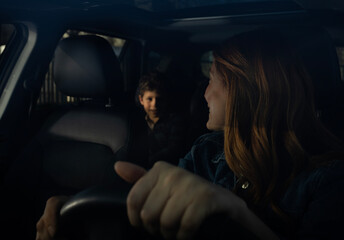 Woman looking back in car at child in backseat at night