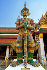 Fototapeta premium Giant Yaksha guardian statue with intricate golden details and a fierce expression stands at the entrance of a Wat Phra Kaew temple symbolizing protection in Thai mythology..