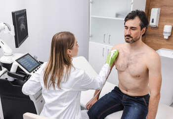 Shoulder ultrasound. Female doctor doing ultrasound scan of male patient with shoulder problem
