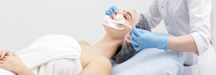 Young woman enjoying a luxurious professional facial mask treatment, enhancing her skin's radiance. A day at the spa, beauty treatment, and relaxing skincare session.