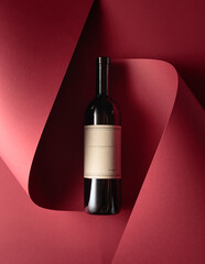 Bottle of red wine with old empty label on a red background.
