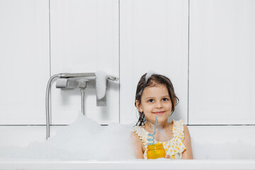 little girl bathes and washes her hair in soap suds.
