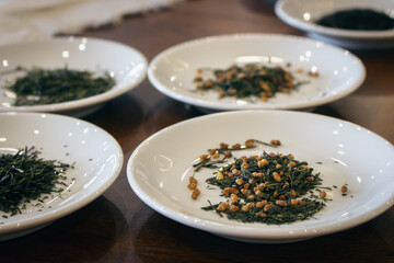 Dried green tea leaves on white plate. Japanese dry tea tasting ceremony. Heap of sencha tea. Healthy lifestyle concept. Asian tea culture.