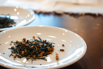 Dried green tea leaves on white plate. Japanese dry tea tasting ceremony. Heap of sencha tea. Healthy lifestyle concept. Asian tea culture.