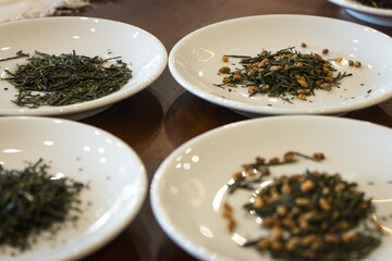 Dried green tea leaves on white plate. Japanese dry tea tasting ceremony. Heap of sencha tea. Healthy lifestyle concept. Asian tea culture.