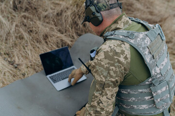 Military Personnel Analyzing Data on a Laptop During a Tactical Operation