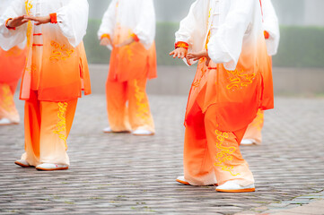 In the foggy morning at the park square, people engage in Tai Chi fitness exercises