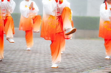 In the foggy morning at the park square, people engage in Tai Chi fitness exercises