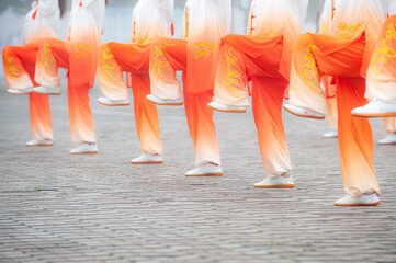 In the foggy morning at the park square, people engage in Tai Chi fitness exercises