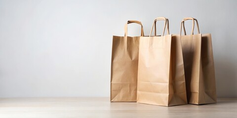 Three kraft paper shopping bags sit on a light wood surface against a neutral backdrop