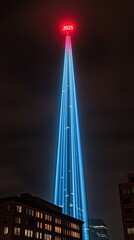 Obraz premium Large skyscraper illuminated with blue lights under a dark sky