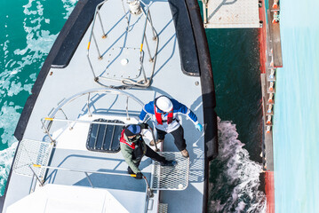 Aerial, top view on the pilot boat - pilot preparing to enter cargo ship using gangway, he will...