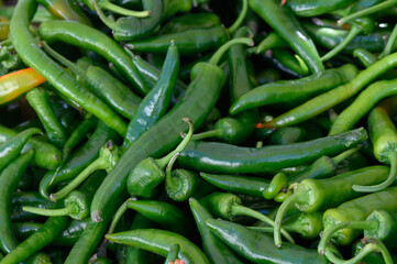 Vibrant green chilies piled high at a bustling market stall in the heart of summer