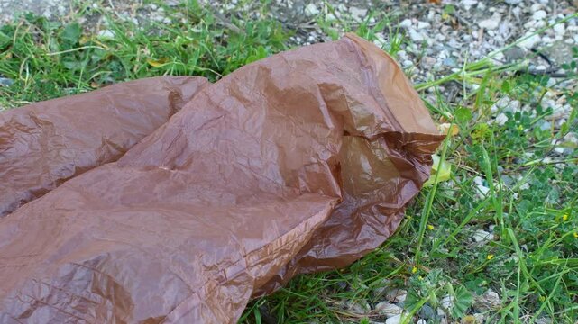 Brown plastic bag blowing in the wind on the ground. Environmental conservation concept. 