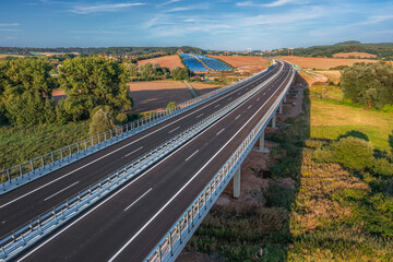 An empty highway bridge stretches across the Czech landscape, seen from above. Highway D6 from Prague to Karlovy Vary and Cheb.