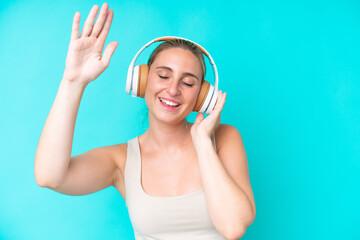 Naklejka premium Young caucasian woman isolated on blue background listening music and dancing