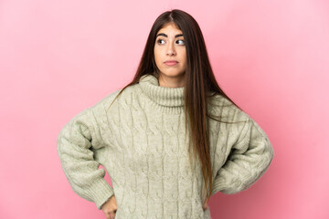 Fototapeta premium Young caucasian woman isolated on pink background making doubts gesture looking side