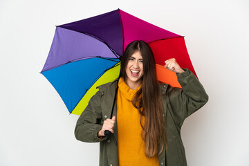 Young woman holding an umbrella isolated on white background doing strong gesture