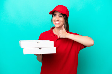 Pizza delivery woman with work uniform picking up pizza boxes isolated on blue background giving a...