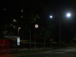 秋の郊外住宅地の夜のバス停留場のある風景
