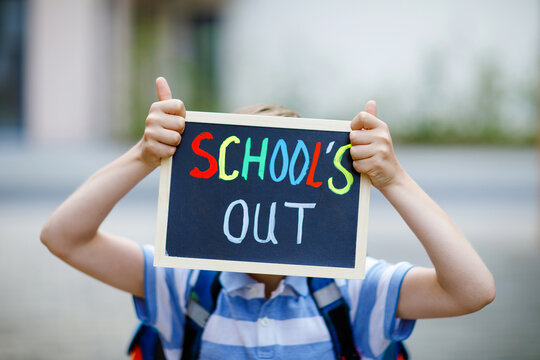 Happy little kid boy with backpack or satchel. Schoolkid on the way to school. Healthy adorable child outdoors With chalk desk for copyspace. Back to school or school's out.