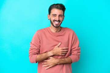 Fototapeta premium Young caucasian man isolated on blue background smiling a lot