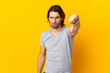 Young handsome man isolated on yellow background showing thumb down with negative expression