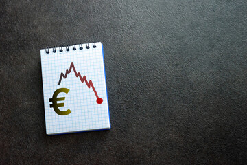 Euro currency symbol and drawing of a negative market trend, written on notepad with black...