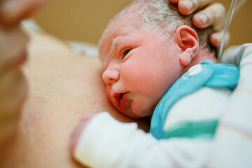 Newborn baby wrapped in blankets after birth. Mother looking for the first time on new born...