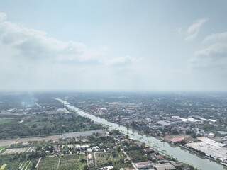 The River's Embrace: An Aerial Glimpse of little town Urban Heart. This drone photograph captures a wide aerial view of Nakhon Pathom, Thailand, with a focus on the river that flows through town