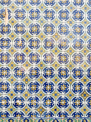 A close-up of colorful, intricate blue and yellow patterned tiles, creating a repeating geometric floral design.