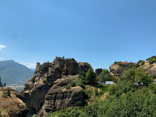 Ancient monastery on towering rock formations under a clear blue sky.