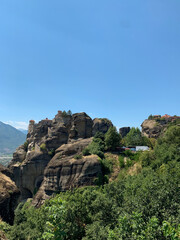 Ancient monastery on towering rock formations under a clear blue sky.