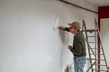 Painter in dirty clothes renovate a wall in a loft