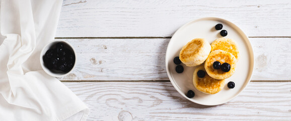 Homemade cottage cheese pancakes and blueberries on a plate on the table top view web banner