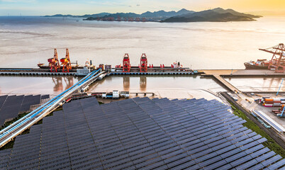 Aerial view of solar panel farm and harbor terminal at sunset