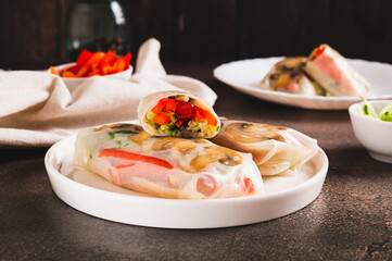 Vegetarian spring rolls with cucumber, pepper and fried mushrooms on a plate on the table