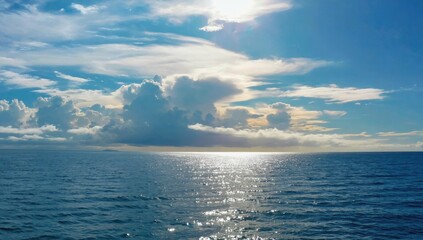 Obraz premium Endless Horizon: Capture the vast expanse of the open sea under a dramatic, cloud-filled sky. The sun casts a brilliant, glistening path across the water, creating a sense of peace. 