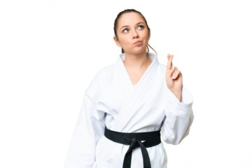 Young blonde woman doing karate over isolated chroma key background with fingers crossing and wishing the best