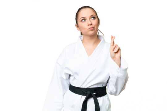 Young blonde woman doing karate over isolated chroma key background with fingers crossing and wishing the best