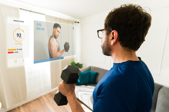 Man lifting weights at home using ar glasses overlaying virtual personal trainer and performance data