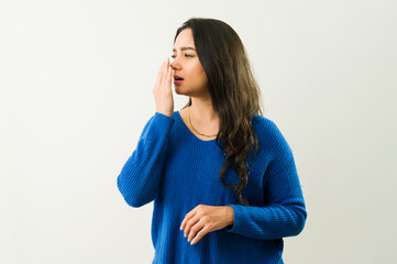 Woman checking breath freshness, hand covering mouth, expressing concern about potential halitosis...
