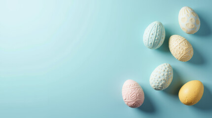 Beautifully decorated Easter eggs with soft pastel colors and intricate patterns placed on a light blue background, creating a festive and elegant holiday composition.