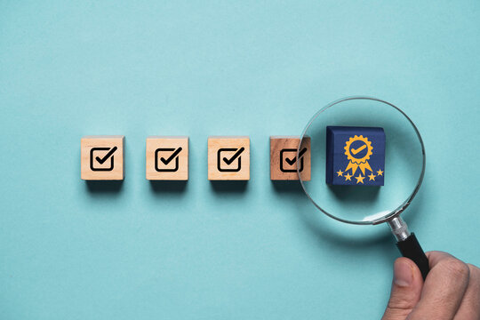 Hand holding magnifier glass to focus the best quality assurance with golden five stars among correct sign mark for guarantee product and ISO service concept.