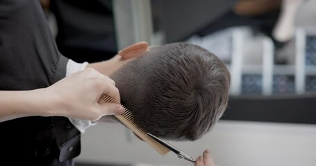 Barber doing a haircut to male client in barbershop close up. Close up of a Barber scissor cutting a young mans hair.
