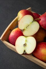 Fresh small organic red apples in a wooden crate on grey table background